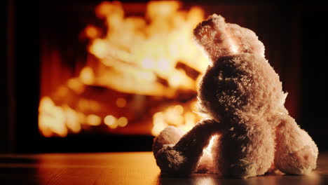 lonely plush rabbit admires the fire in the fireplace insert slow motion video