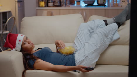 unhappy woman watching television alone on christmas eve