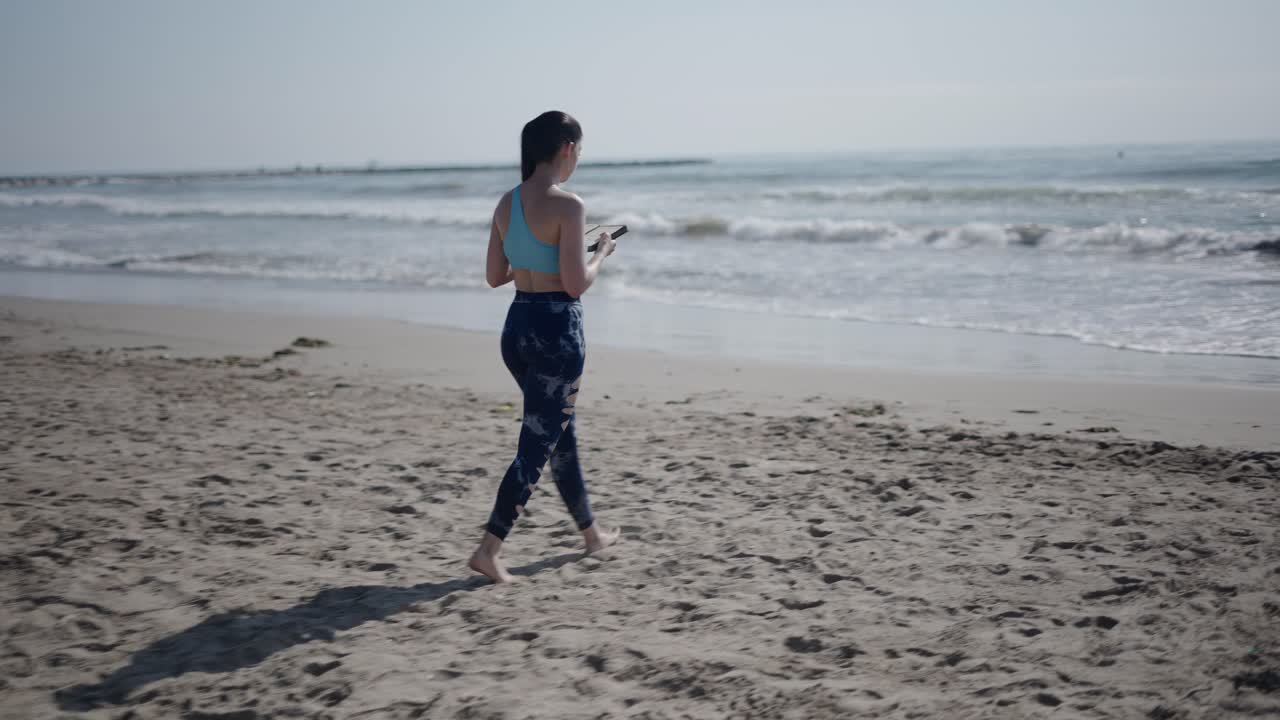 Woman Walking on the Beach with a Phone