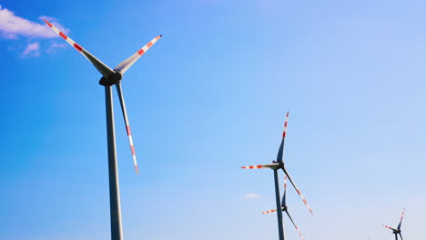 wind turbines producing energy. tall wind turbines spin against a clear blue sky, producing sustainable energy in a rural landscape during daytime