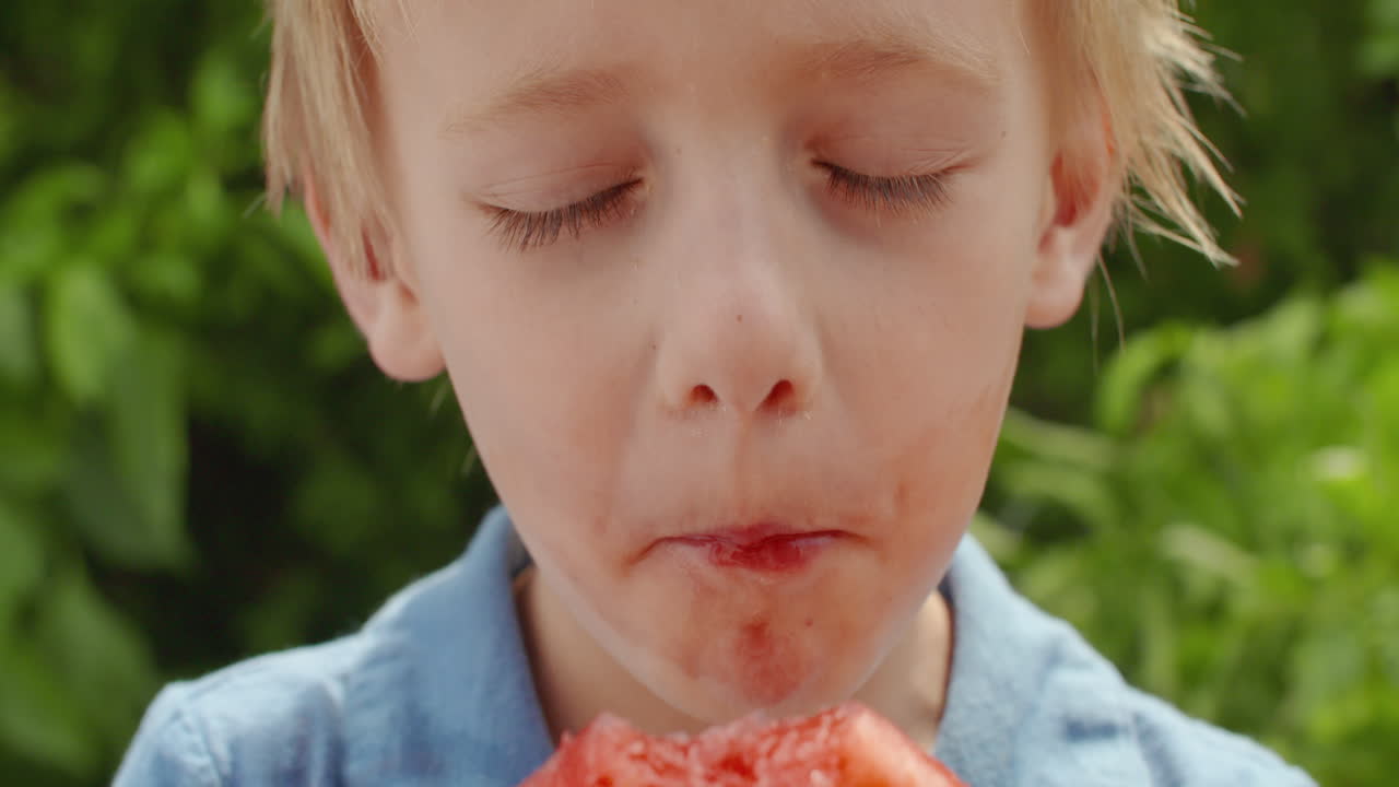 Happy little boy eating a slice of juicy watermelon