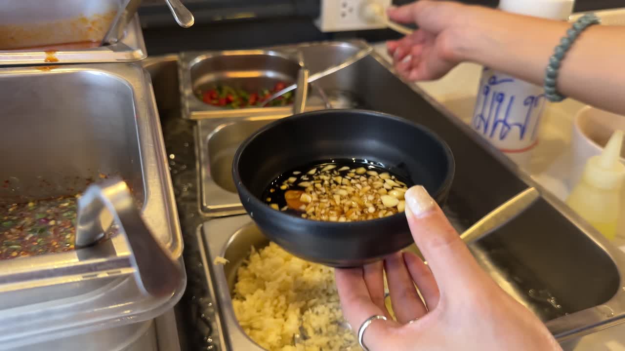 Hands prepare a flavorful Korean BBQ sauce in a Bangkok kitchen, mixing ingredients with precision under warm lighting