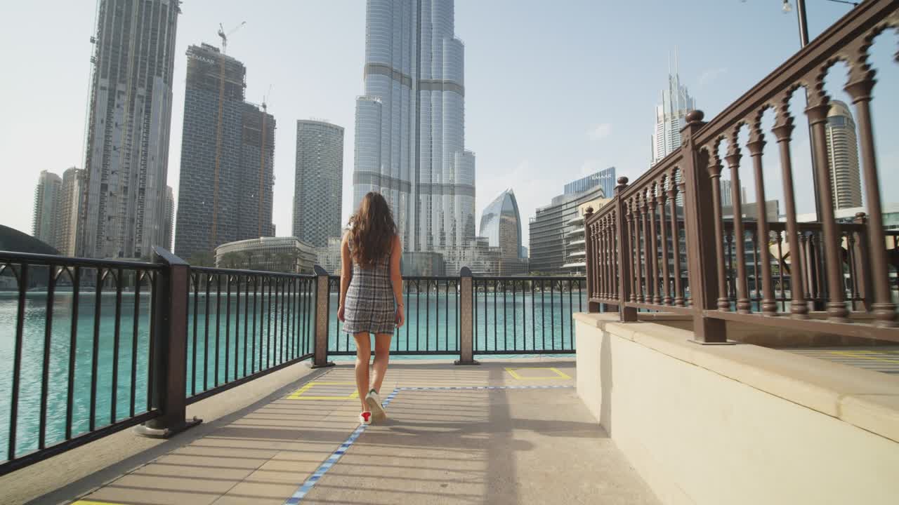 Woman walking by the pool near Burj Khalifa skyscraper in Dubai. Following a tourist exploring famous tourist destinations in Dubai