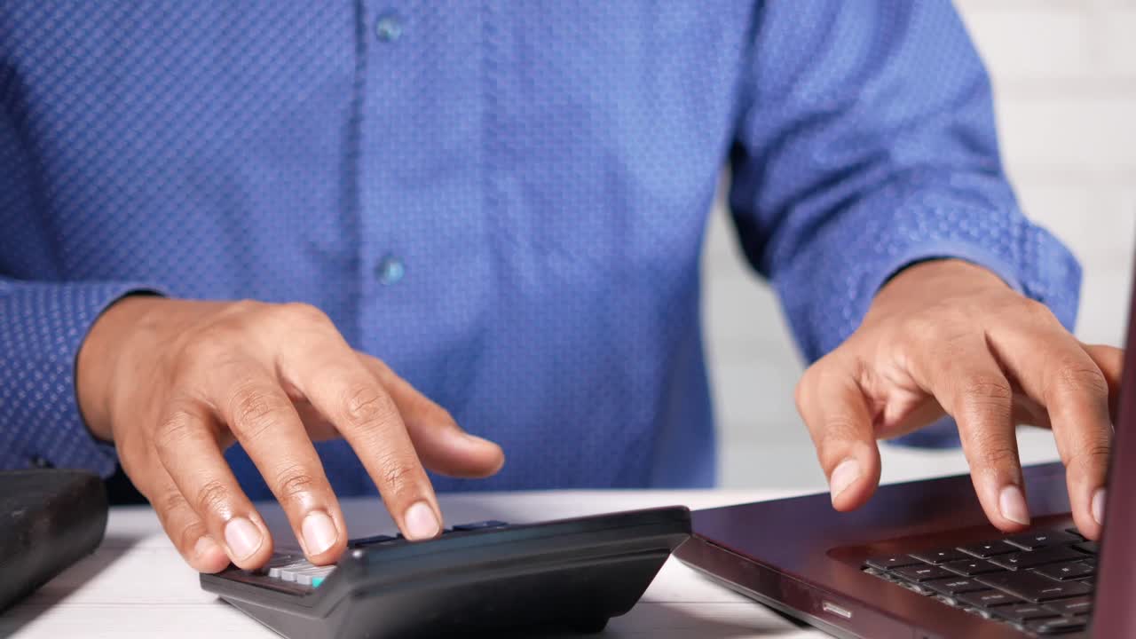 hombre de negocios trabajando en una computadora portátil y una calculadora