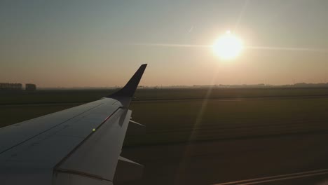 vista a través de la ventana del avión antes del despegue. ala de un avión al amanecer en el aeropuerto. el avión se prepara para el vuelo y toma una vista de la pista desde la ventana de la aeronave