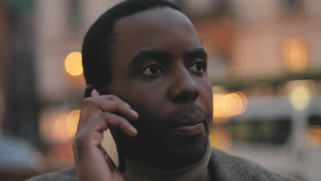 close-up view of african american young man talking on the smartphone in the street in the evening