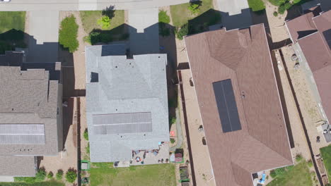 Close-up-overhead-aerial-view-of-suburban-neighborhood-in-the-summer-with-renewable-and-green-rooftop-solar-panels-to-help-the-climate