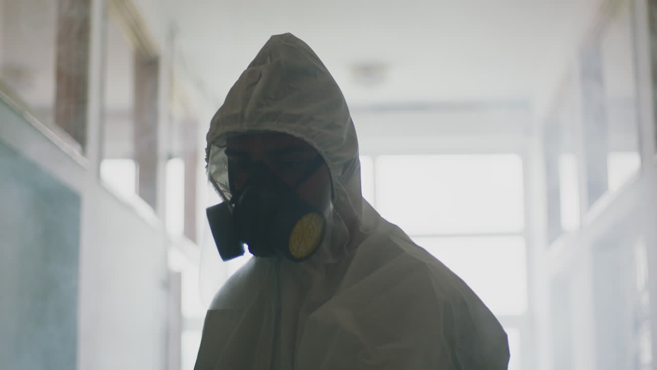 Person in hazmat suit disinfecting area