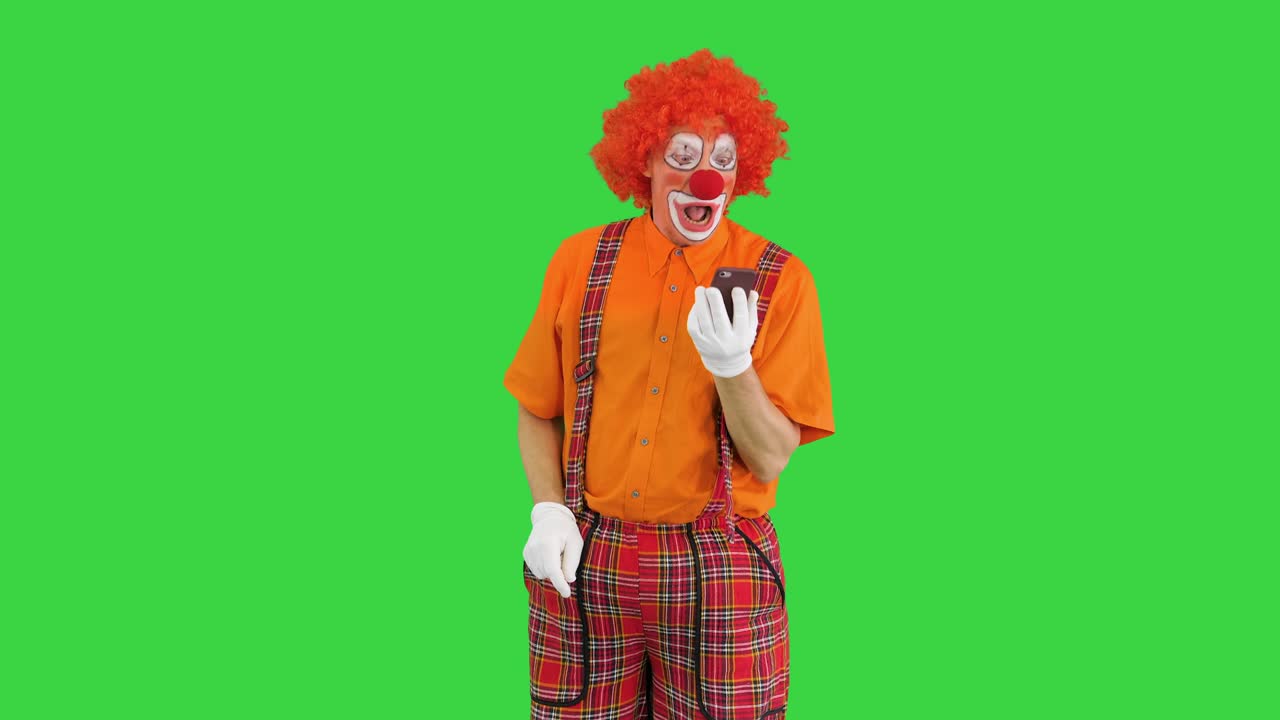payaso con teléfono inteligente haciendo una llamada en una pantalla verde, clave de croma