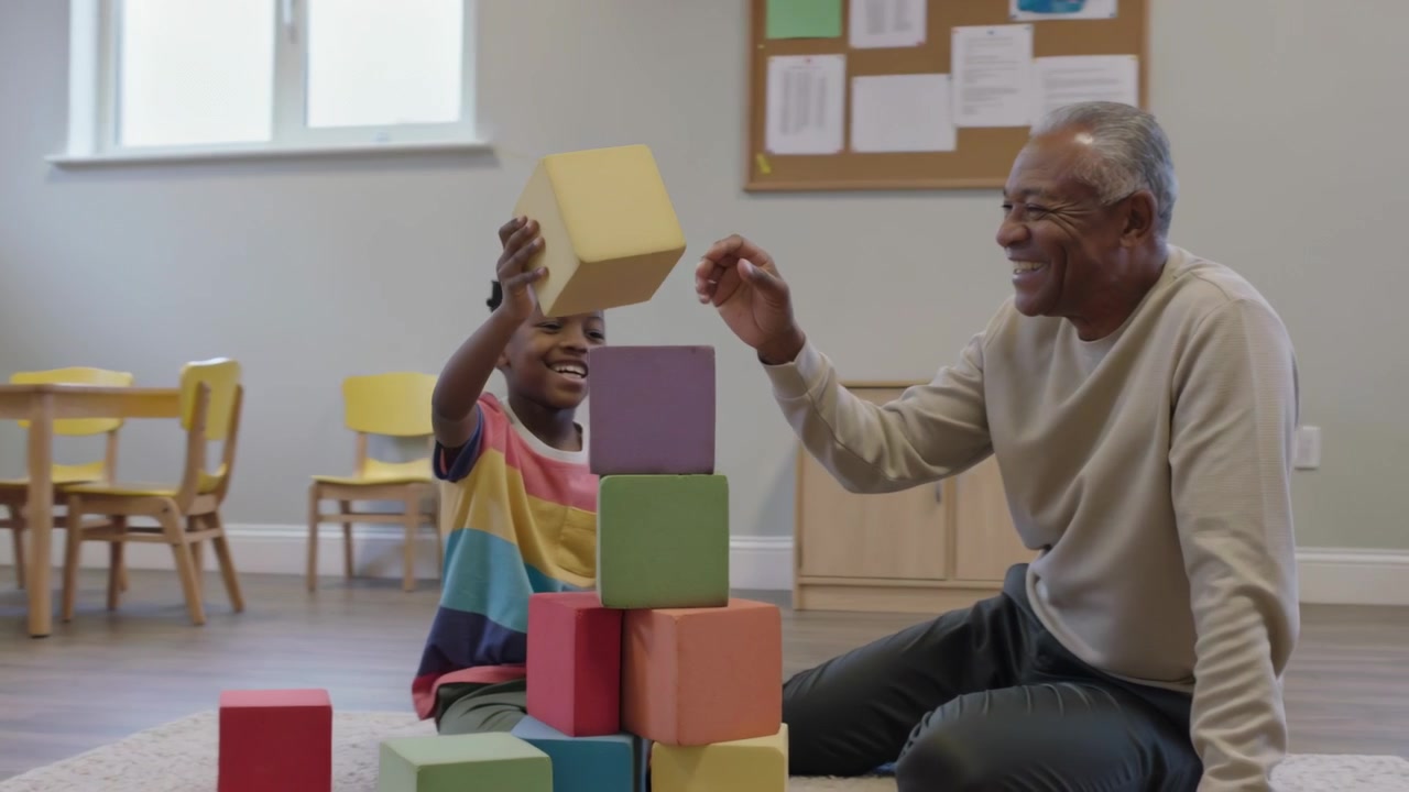 Reaching senior man placing purple block, child finishing foam-block tower in playroom, beige top