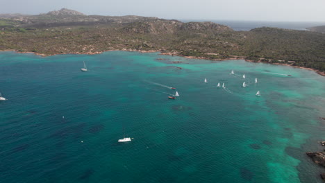 wonderful aerial view with circular motion over sailboats sailing on the island of caprera in sardinia