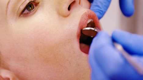 Dentist-examining-a-female-patient-with-tools