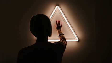 person interacting with a glowing neon triangle