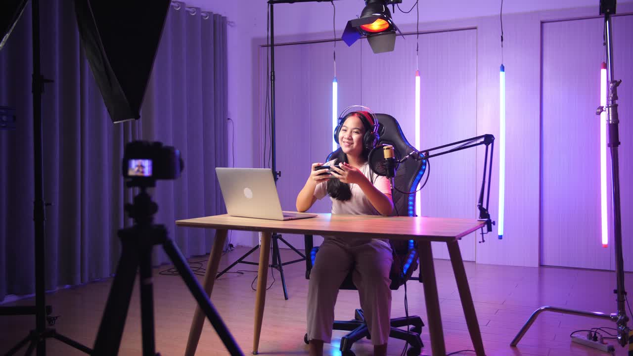Asian Kid Girl Holding Mobile Phone And Talking To Camera While Live Stream, Professional Light Equipment