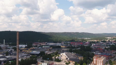 Industrial-chimney-and-living-buildings-of-small-town-in-Sweden,-aerial-tilt-down-shot