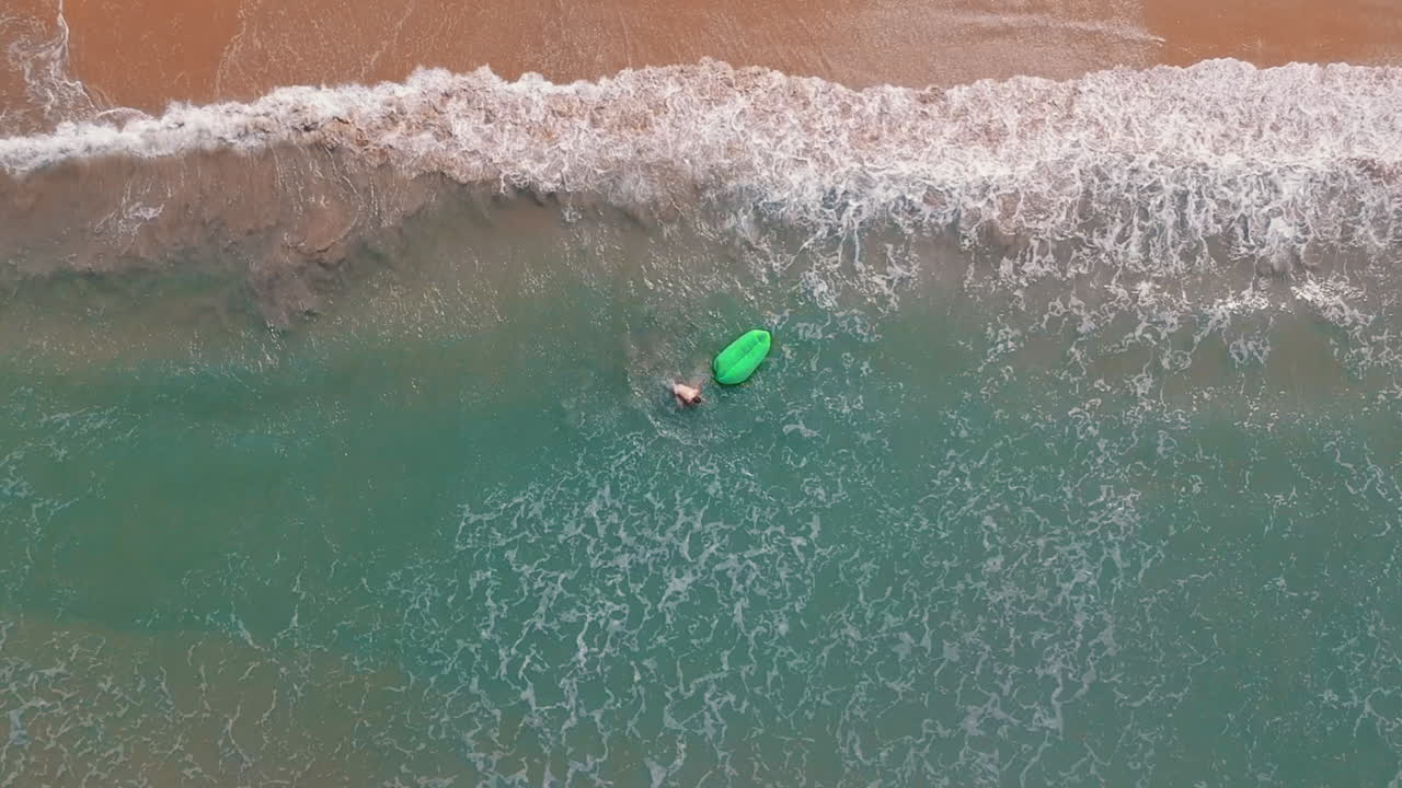 joven blanco caminando por una playa de agua azul clara en una isla tropical
