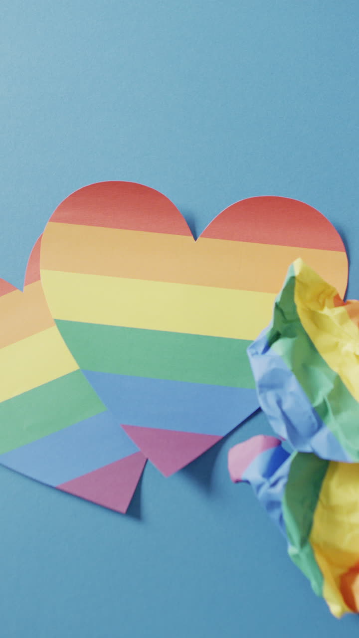 Vertical video of rainbow heart over blue background