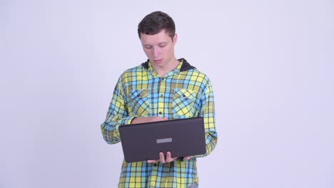 joven feliz, guapo y hipster con una computadora portátil
