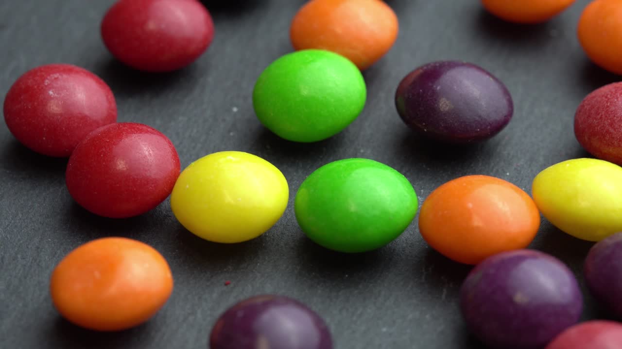 los dulces de frutas de colores giran sobre un fondo negro, los dulces de marco de colores
