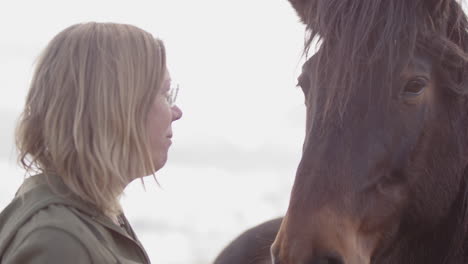 woman kisses muzzle of horse during equine-assisted therapy workshop, closeup