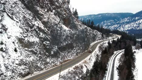 Ein-Sattelschlepper,-Der-Ein-Boot-über-Einen-Kalten-Highway-5-Im-North-Thompson-River-Valley-In-Der-Nähe-Von-Kamloops-Transportiert,-Mit-Einer-Engen-Straße-Und-Einer-Geschützten-Felswand-Daneben