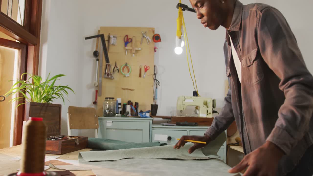 Focused african american craftsman preparing leather in leather workshop