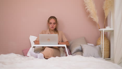 Frelance-woman-does-research-work-on-computer-on-soft-bed