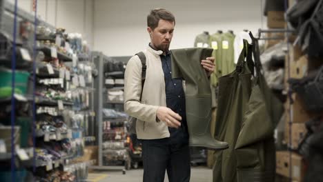 hombre mirando botas de pesca en una tienda