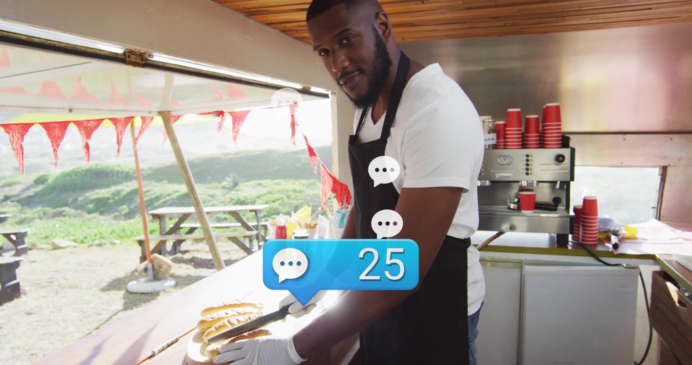 Male vendor arranging buns with tongs at food truck, responding to rising comment counter, laughing