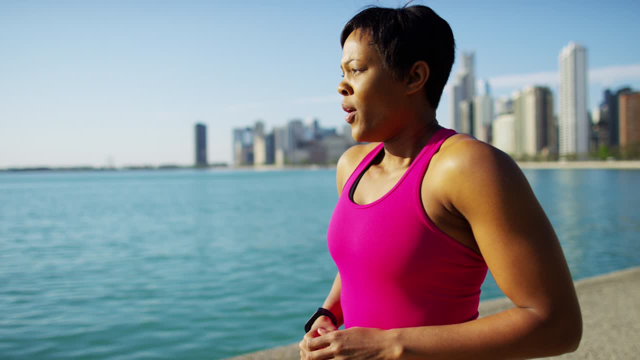mujer étnica que usa un reloj inteligente descansando después de correr