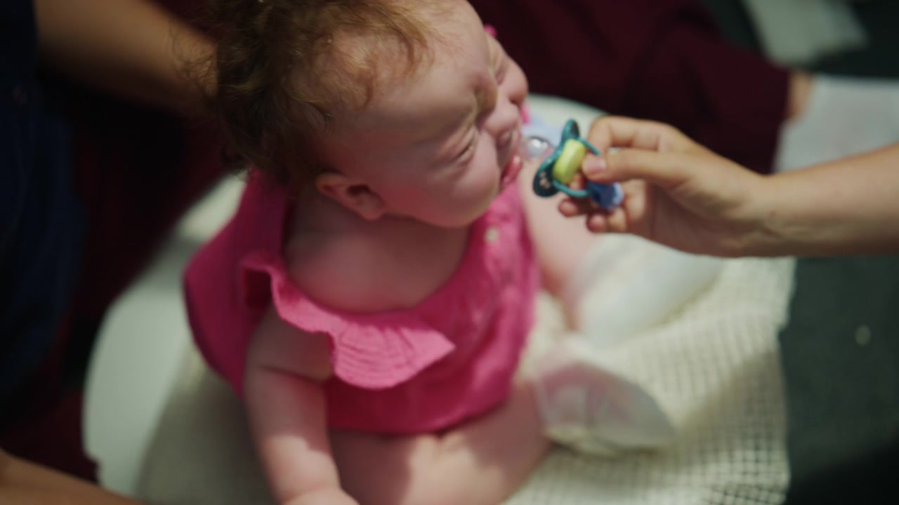 Infant sitting comfortably while a caregiver provides gentle physical support and positioning techniques during an early childhood therapy session