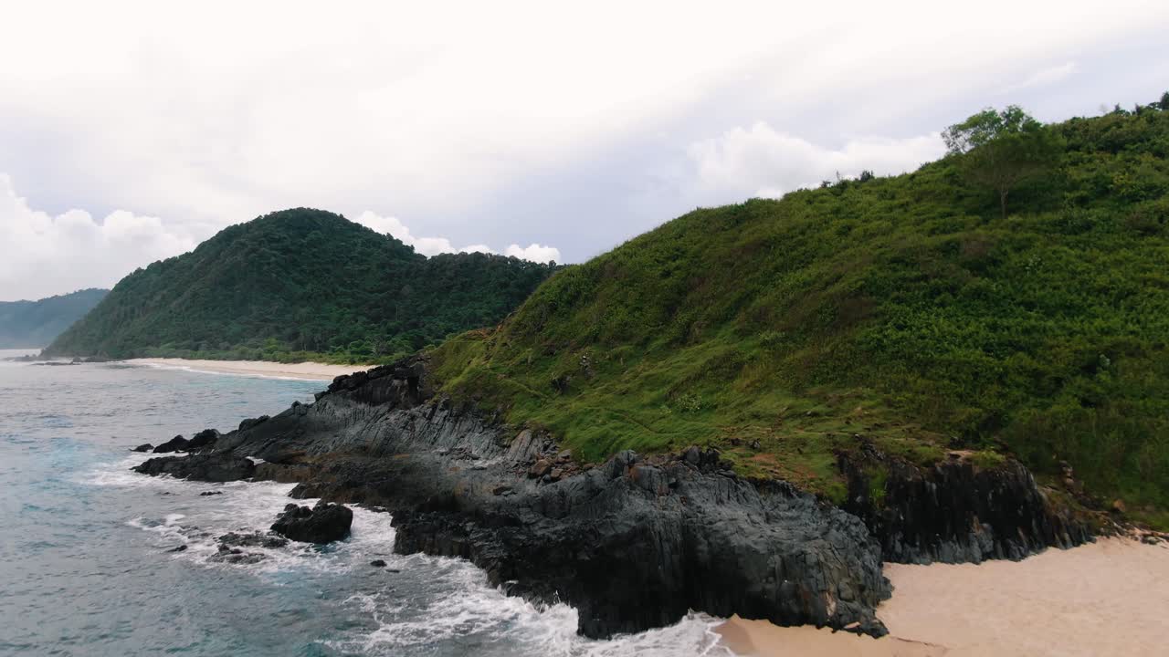 amplia toma aérea como volar sobre una playa de arena remota y abandonada, en una isla volcánica, rocas de basalto negro en el océano