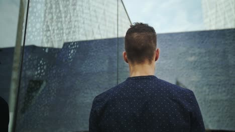 Well-Dressed-Entrepreneur-businessman-Young-Attractive-Trendy-Man-looking-into-his-own-reflection-on-a-modern-building-window-and-then-walks-away-in-slow-motion