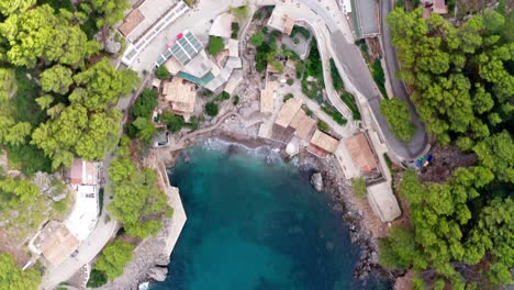 Hotel-complex-in-bay-with-blue-sea-high-angle-view-of-mansion-overlooking-the-ocean,-drone-aerial