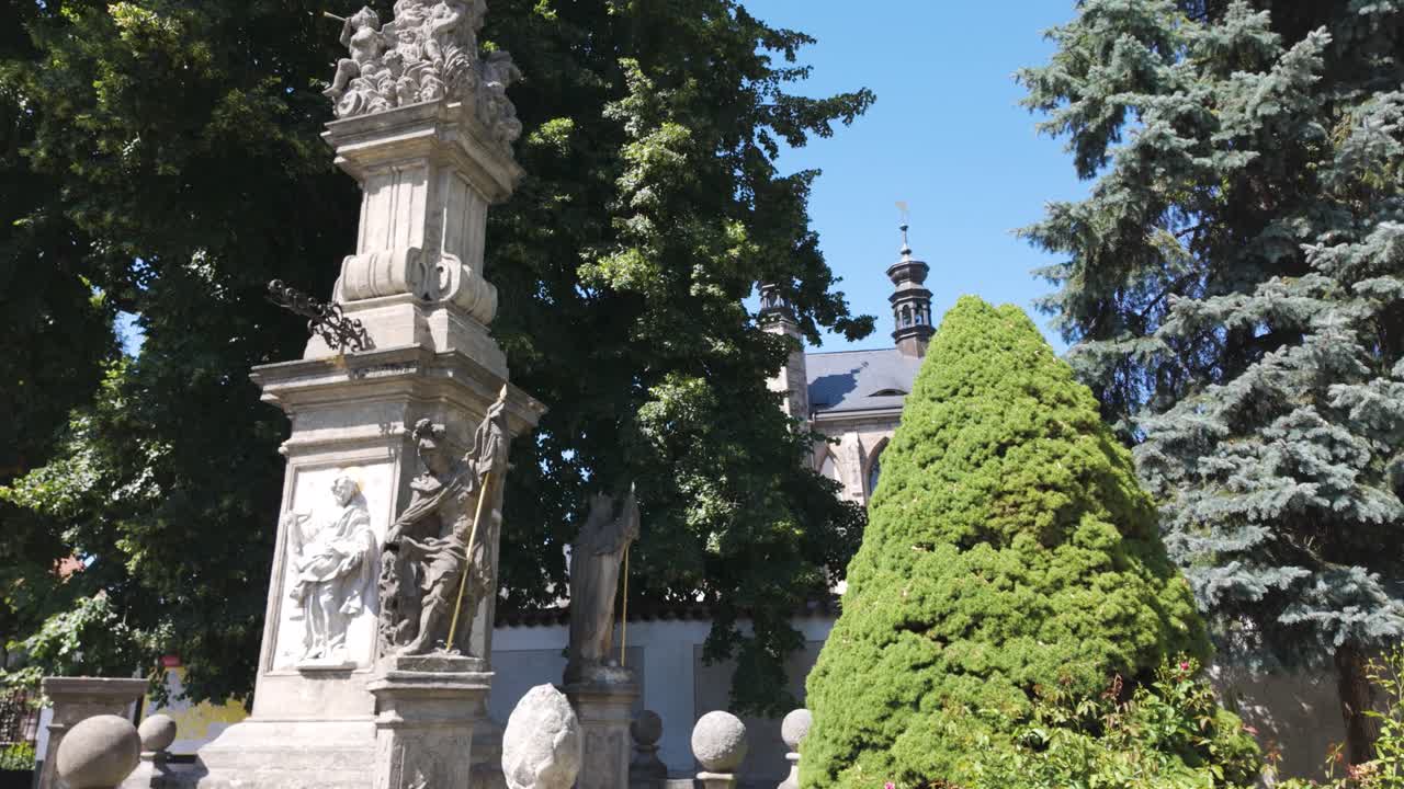 Tranquil scene capturing the historic gardens outside Sedlec Ossuary, with ornate stone statues and lush greenery in the suburbs of Kutna Hora, Czech Republic.