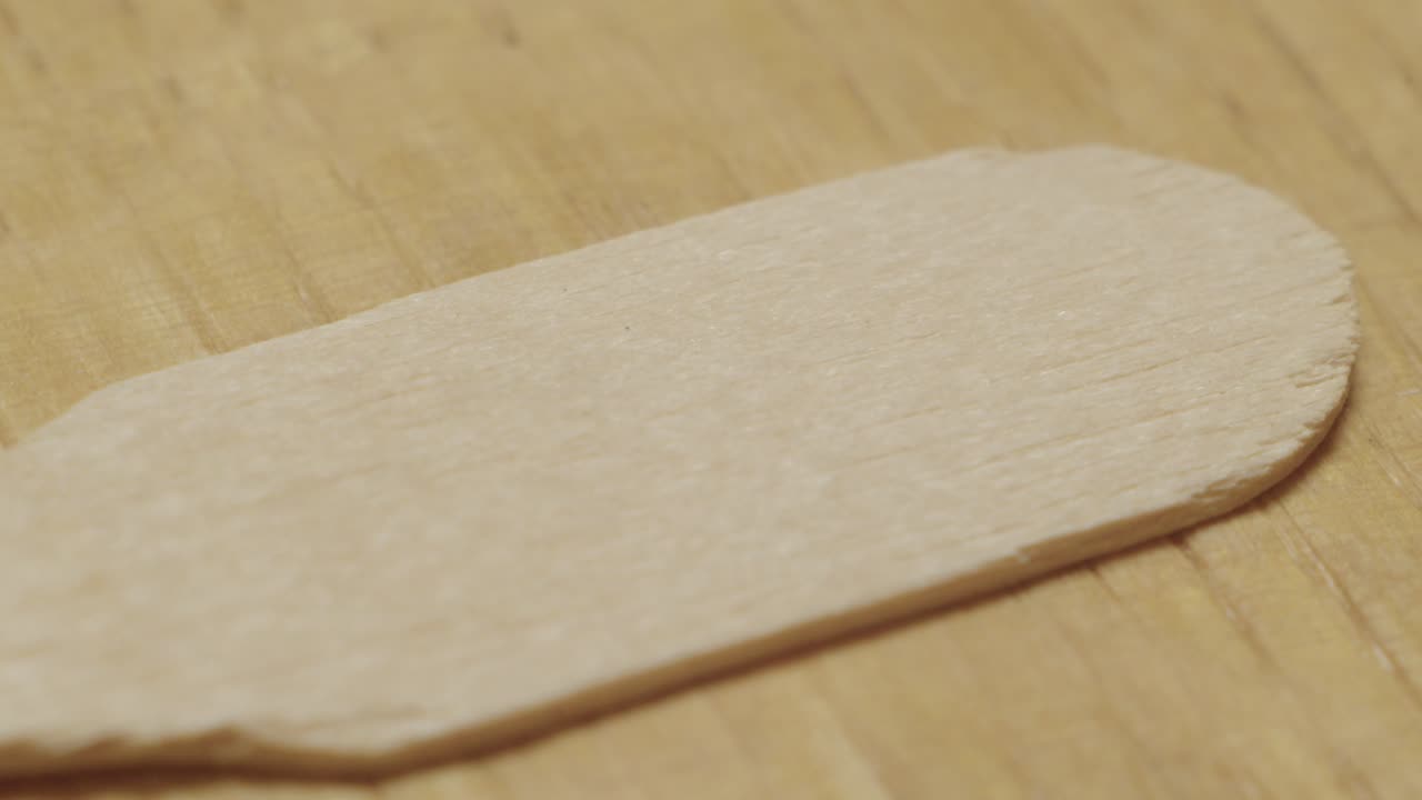 Macro shot of wooden surface showing light grain and smooth brown tones. Perfect for craftsmanship and organic design visuals
