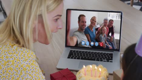 caucasian mother and daughter sitting at table using laptop having birthday video call