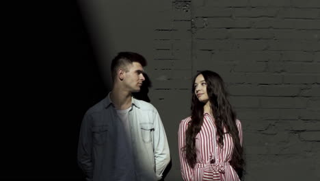 young couple posing by a brick wall