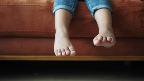 child sitting on a sofa with bare feet