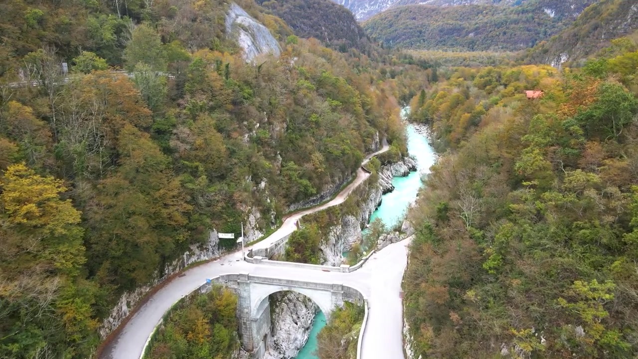 Přelet dronu nad Kobaridským mostem sledující tyrkysovou řeku Soču alpským údolím, Slovinsko