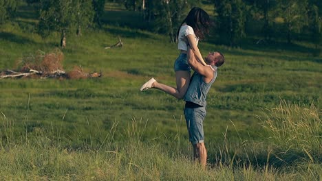 Hübscher-Mann-In-Jeansweste-Und-Shorts-Hebt-Brünette-Dame-Hoch