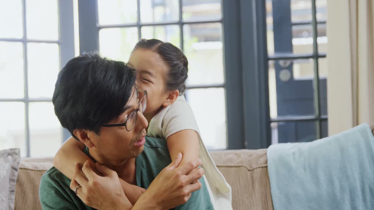 미소 짓는 아버지와 딸이 거실 4k의 소파에서 재미를 느끼고 있습니다.