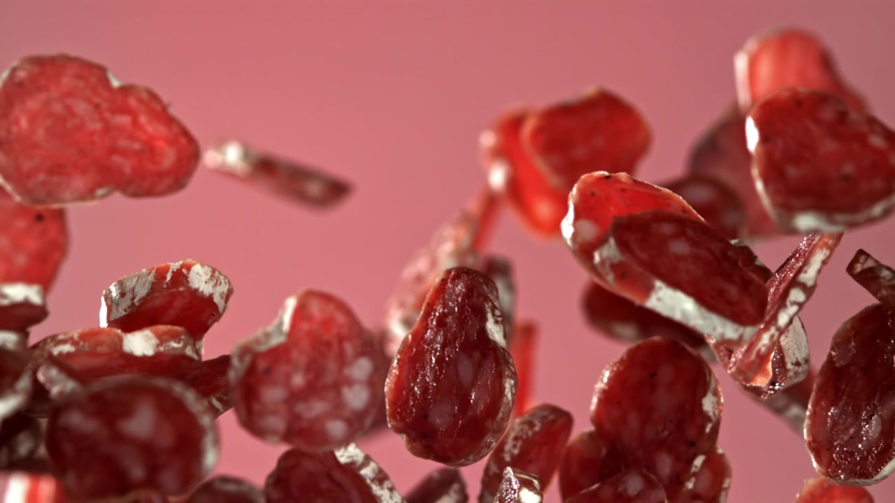 Salami Slices Falling and Floating in Slow Motion on a Pink Background