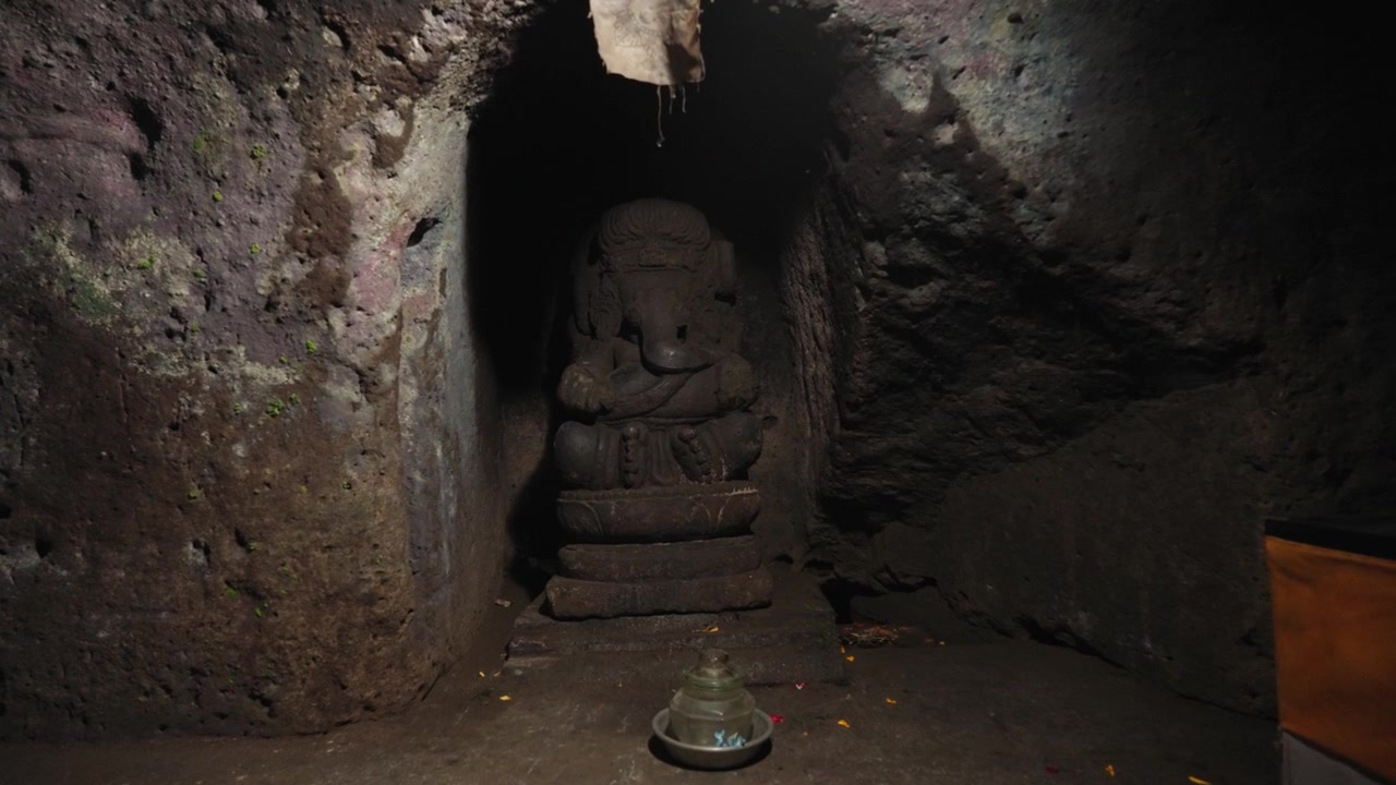 Antica statua in pietra di Ganesha all'interno di un tempio rupestre buio