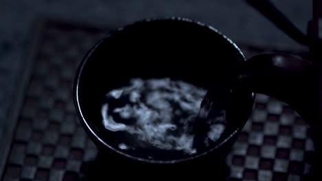 tetera oriental de hierro fundido que vierte té en una taza a la luz de la luna
