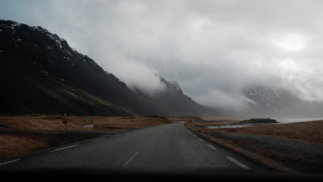 Driving-along-Route-1-in-Northern-Iceland,-featuring-expansive-views-of-mountains,-clouds,-and-coastal-landscapes-with-grass