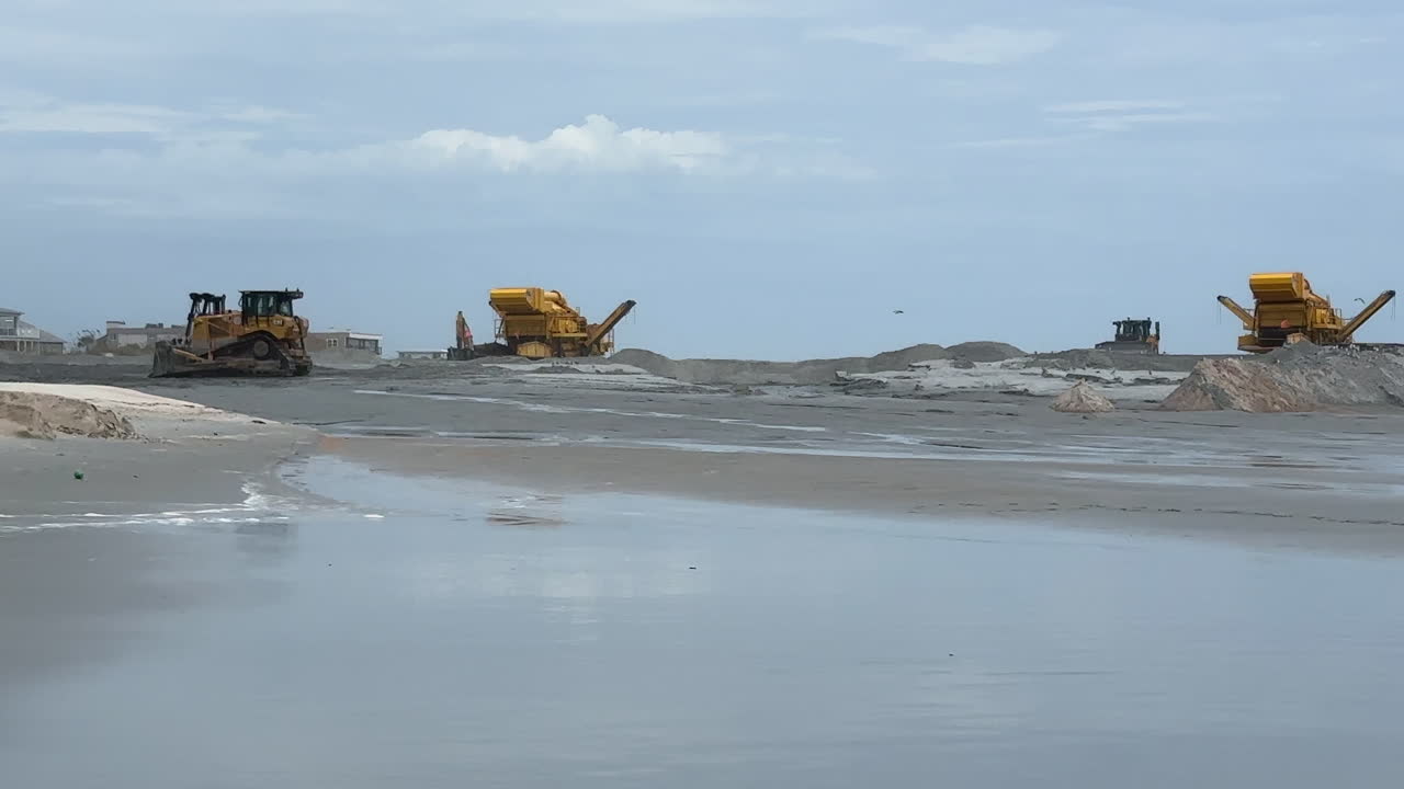 Birds flying over sand during coastal beach replenishment project