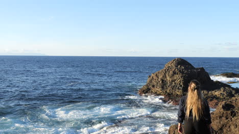 scatto di una donna che ammira le onde del mare e che si trovano sulla costa del comune di galdar, sull'isola di gran canaria e durante il tramonto