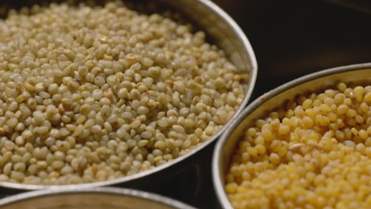 Different types of millets in stored in steel bowls, 4k, close up, push in shot