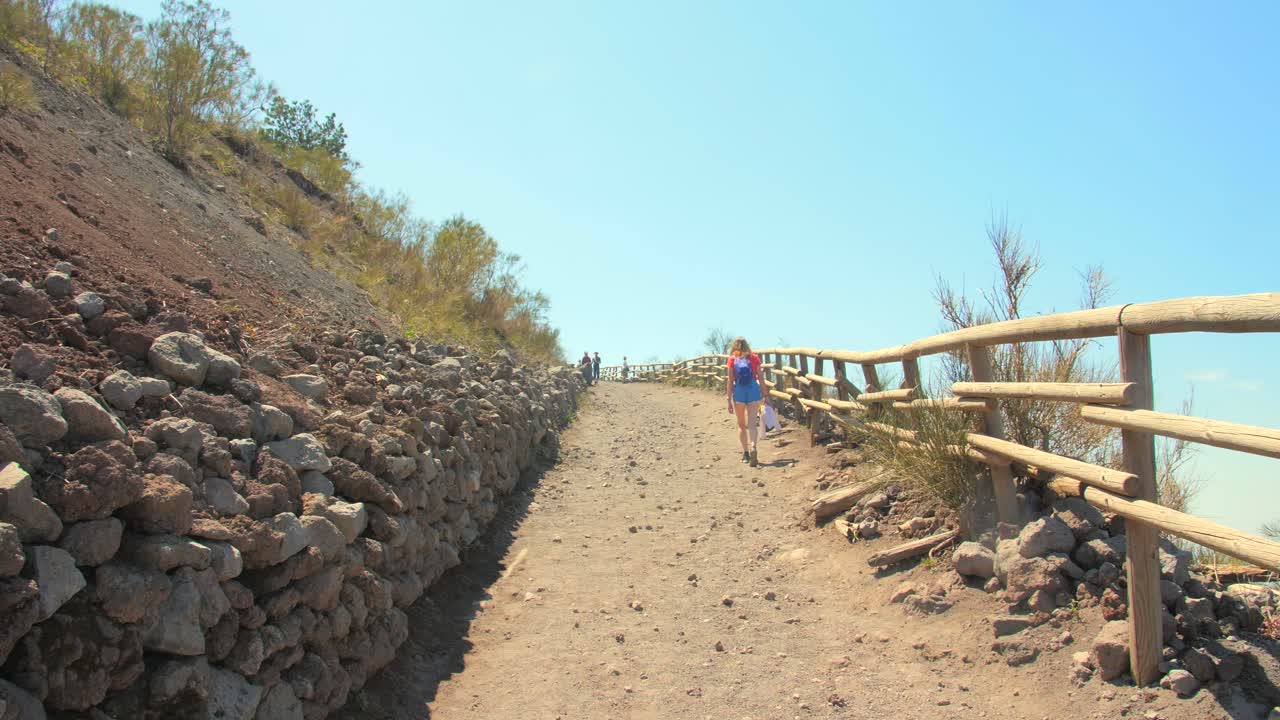 mujer solitaria camina por el sendero hacia el cráter del monte vesubio en campania, italia